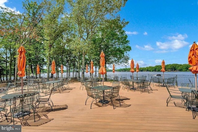 wooden terrace with a water view and outdoor dining area