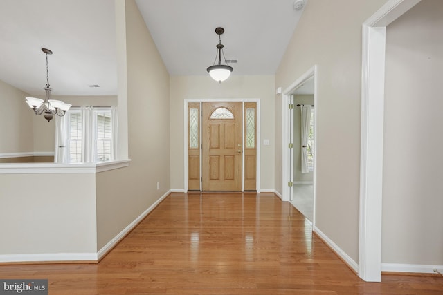 entrance foyer with baseboards, light wood finished floors, and a notable chandelier