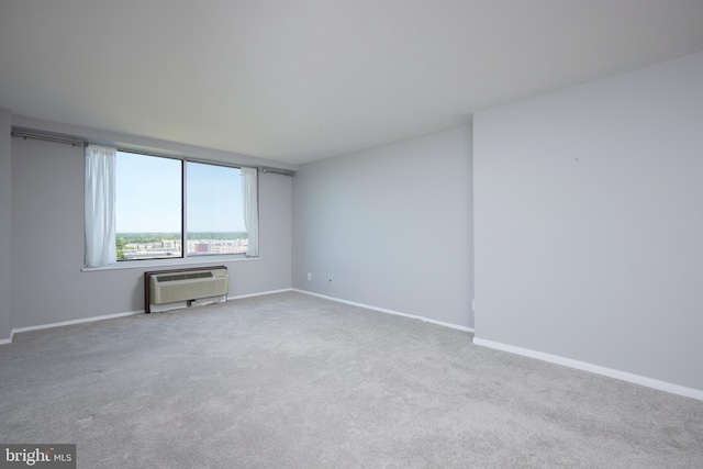 carpeted spare room featuring baseboards and a wall mounted AC
