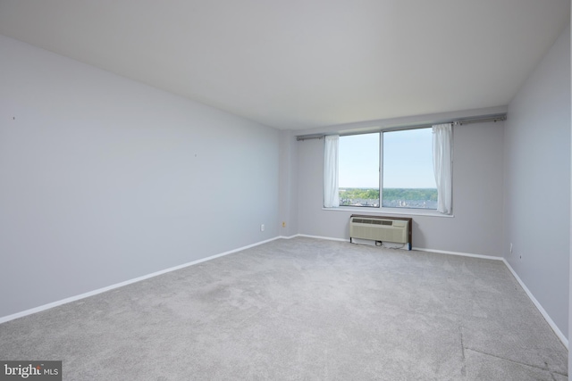 carpeted spare room featuring baseboards and a wall unit AC