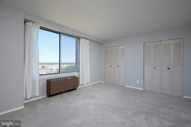 unfurnished bedroom featuring carpet floors, baseboards, and two closets