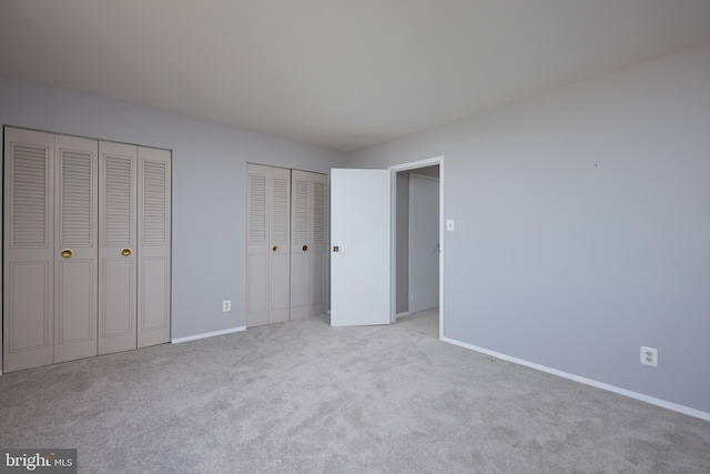 unfurnished bedroom with baseboards, carpet flooring, and multiple closets