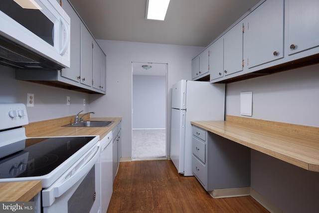 kitchen with dark wood-style flooring, a sink, built in study area, white appliances, and wood counters