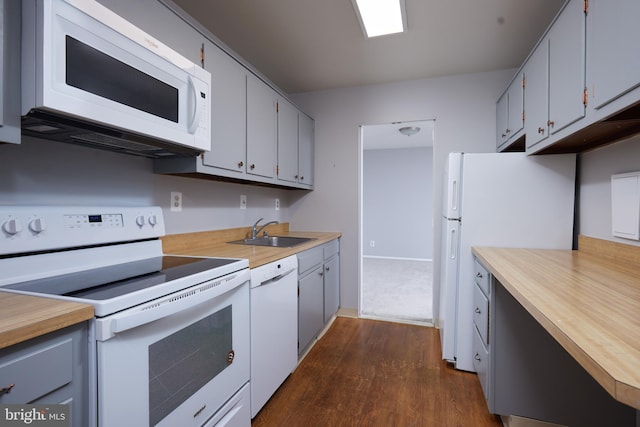 kitchen featuring white appliances, butcher block countertops, dark wood-type flooring, a sink, and gray cabinetry