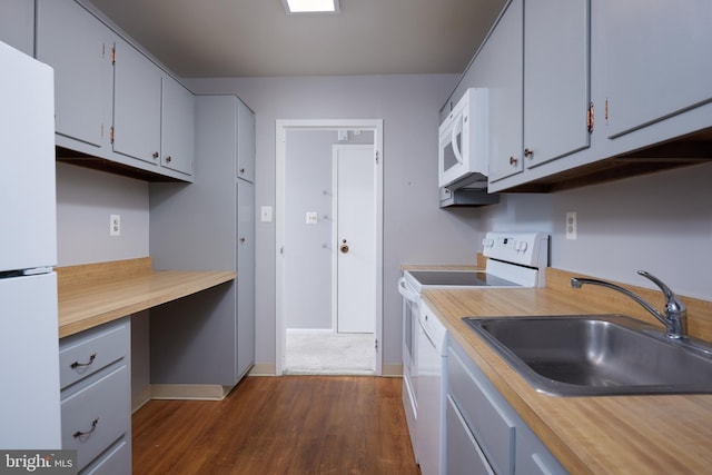 kitchen featuring white appliances, baseboards, dark wood-style floors, light countertops, and a sink