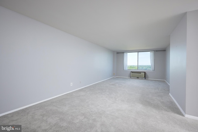 spare room with carpet floors, baseboards, and a wall mounted air conditioner