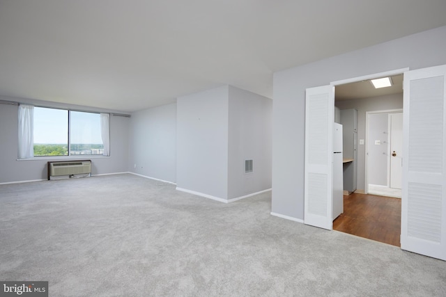 carpeted spare room with baseboards, a wall unit AC, and visible vents