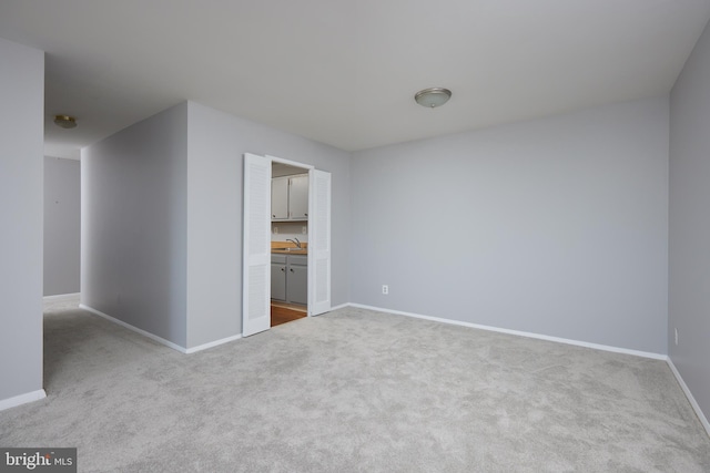 empty room with a sink, baseboards, and carpet flooring