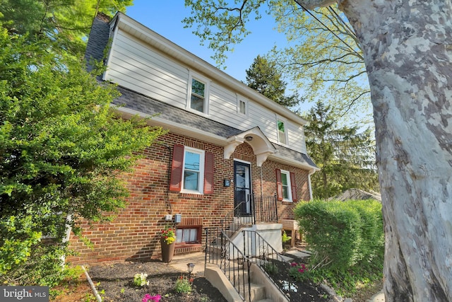 exterior space with a shingled roof and brick siding