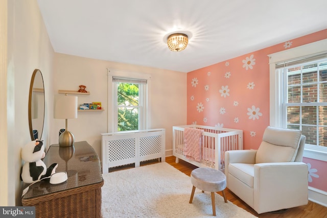 bedroom featuring baseboards, wallpapered walls, and wood finished floors