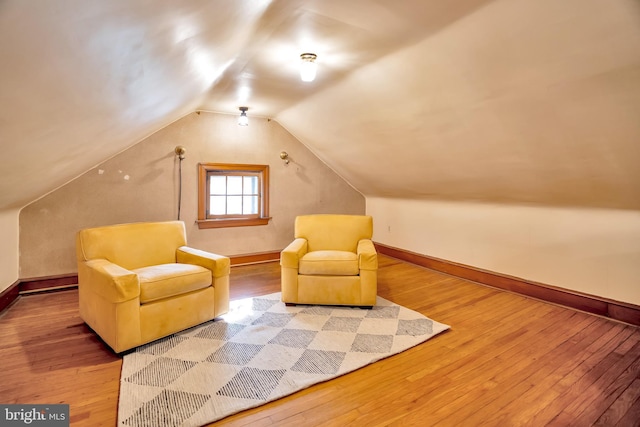 sitting room with baseboards, lofted ceiling, and hardwood / wood-style flooring