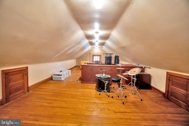 additional living space with baseboards, vaulted ceiling, and light wood-style floors