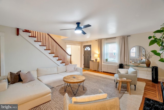 living area with radiator, ceiling fan, stairs, and wood finished floors