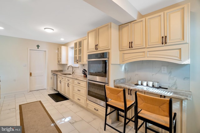 kitchen with marble finish floor, appliances with stainless steel finishes, and cream cabinetry