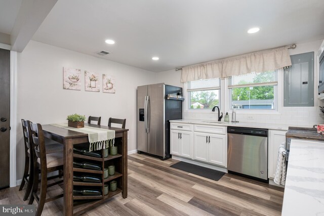 kitchen featuring visible vents, a sink, light stone counters, light wood-style floors, and stainless steel appliances