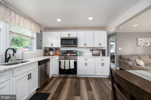 kitchen with open floor plan, white cabinetry, a sink, backsplash, and stainless steel appliances