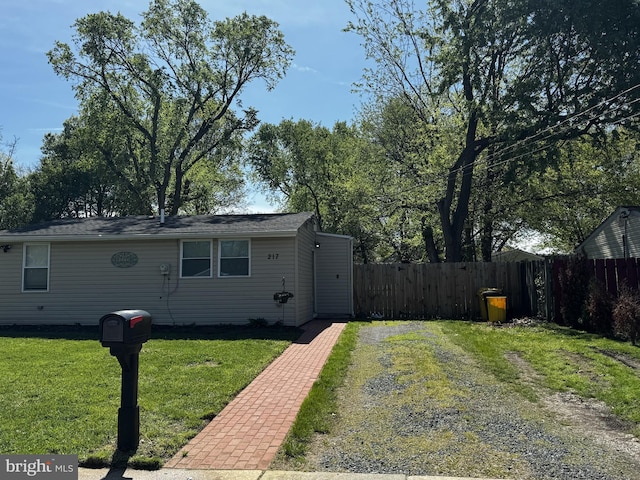 view of front facade featuring fence, driveway, and a front lawn