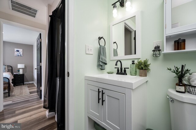 bathroom with vanity, toilet, wood finished floors, and visible vents