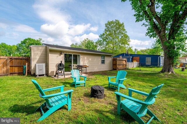 rear view of property with a lawn, a fire pit, and a fenced backyard