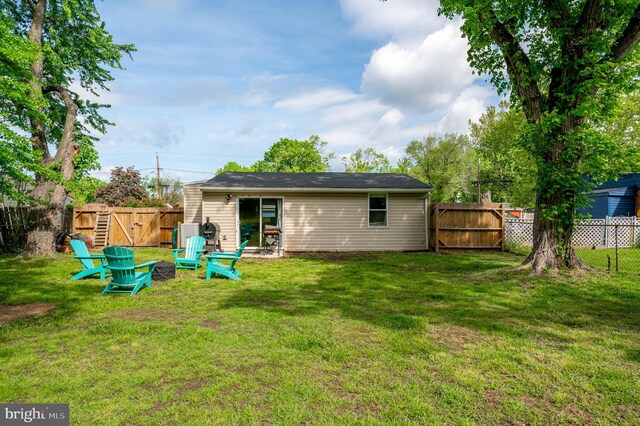 back of property featuring a fenced backyard, a gate, and a yard