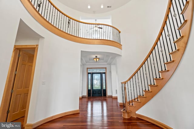 entrance foyer with hardwood / wood-style flooring, a high ceiling, stairs, and baseboards
