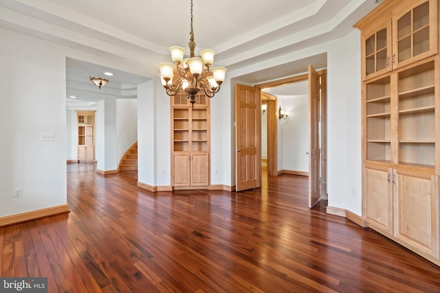 unfurnished dining area with a chandelier, dark wood finished floors, baseboards, stairs, and built in features