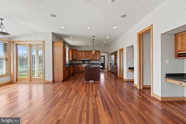 kitchen with dark countertops, dark wood-style flooring, a center island, baseboards, and lofted ceiling