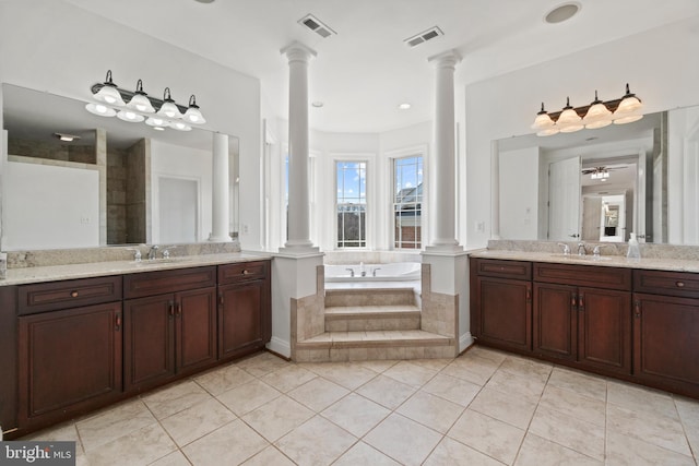 bathroom with decorative columns, a bath, tile patterned floors, and two vanities