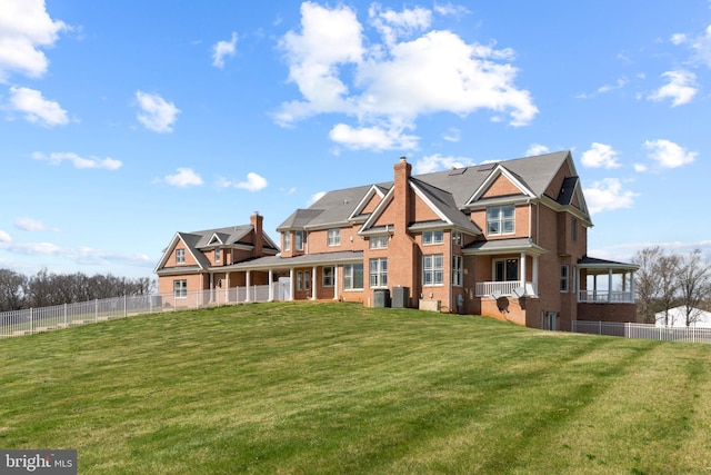 rear view of house featuring a chimney, central AC unit, and brick siding