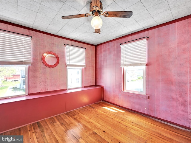spare room featuring wood walls, ceiling fan, and hardwood / wood-style floors