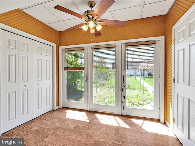 doorway to outside featuring wood walls, ceiling fan, and wood finished floors