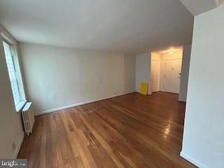 spare room featuring wood finished floors and radiator heating unit
