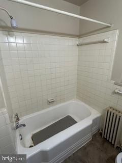 bathroom with radiator heating unit, tile walls, and shower / tub combination