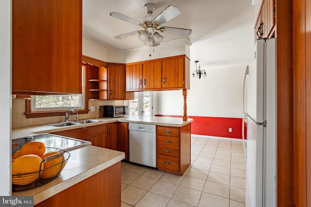 kitchen with white appliances, light countertops, brown cabinets, a sink, and backsplash