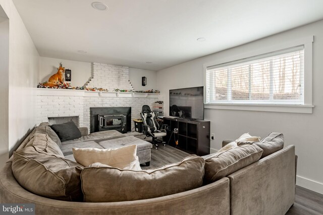 living area featuring a brick fireplace, baseboards, and wood finished floors