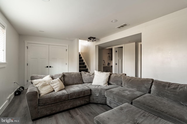 living area with baseboards, visible vents, wood finished floors, and stairway