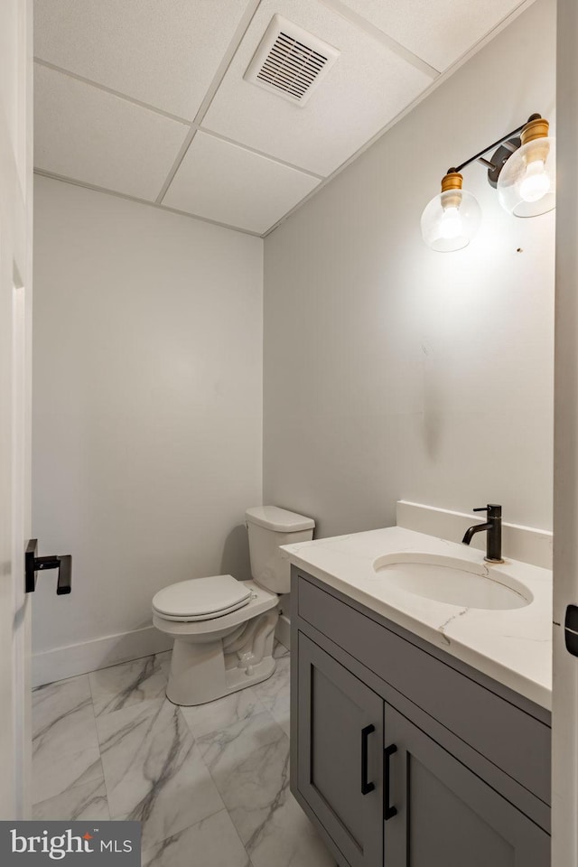half bath with toilet, visible vents, marble finish floor, and vanity