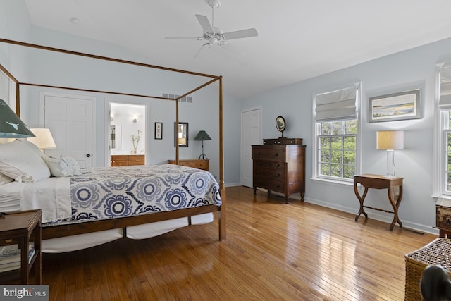 bedroom with visible vents, baseboards, connected bathroom, light wood finished floors, and vaulted ceiling