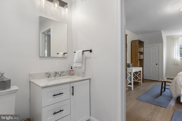 bathroom featuring vanity, baseboards, wood finished floors, and toilet