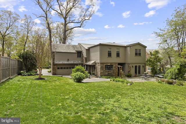 back of property with a patio, a lawn, fence, and stone siding