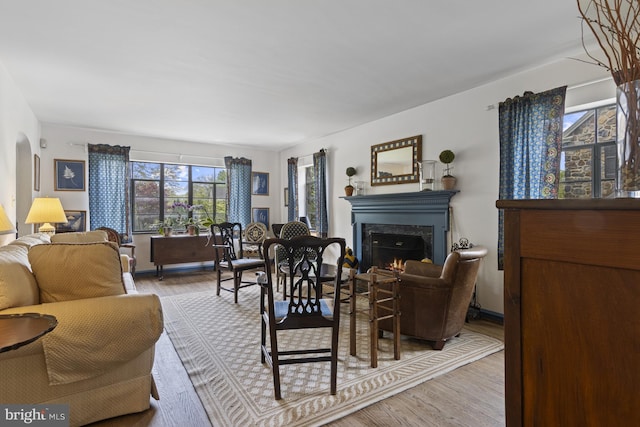 living area with a premium fireplace, arched walkways, and wood finished floors
