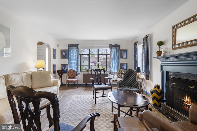 living room with arched walkways, a fireplace, and wood finished floors