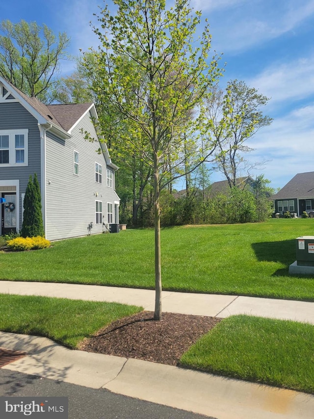 view of property exterior with a lawn and central AC
