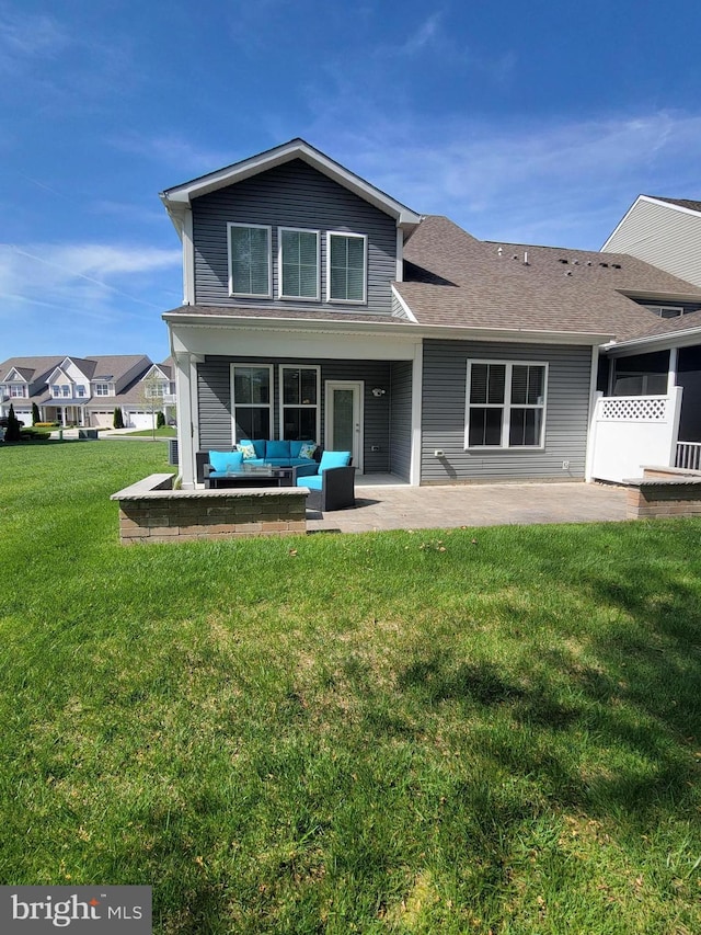rear view of house with a patio, outdoor lounge area, a lawn, and roof with shingles