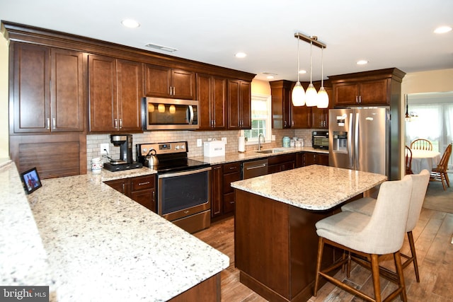 3505 Fox Ridge Rd, Waldorf, MD 20601 - kitchen featuring stainless steel appliances, wood finished floors, a sink, light stone counters, and a kitchen island