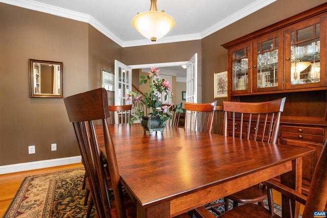 dining space with crown molding, baseboards, and wood finished floors