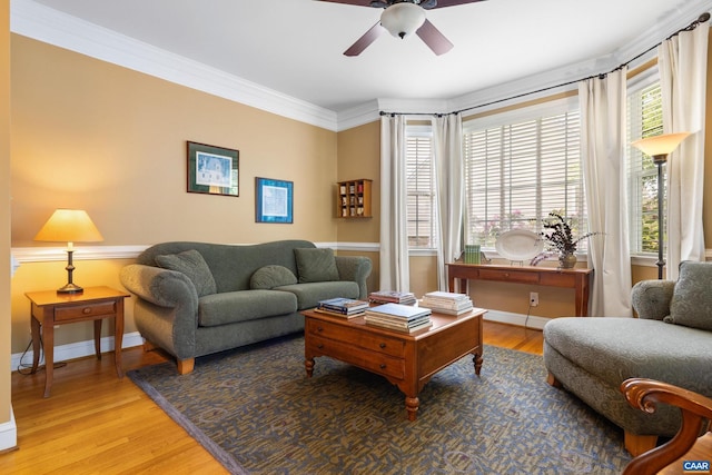 living area featuring a healthy amount of sunlight, baseboards, ceiling fan, and wood finished floors