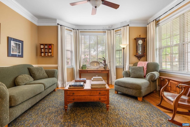sitting room with a ceiling fan, wood finished floors, and ornamental molding