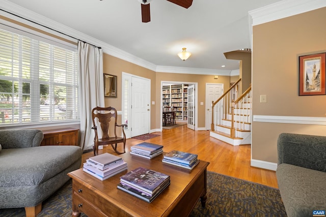 living room featuring ornamental molding, stairs, wood finished floors, baseboards, and ceiling fan