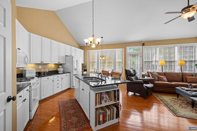 kitchen featuring a sink, vaulted ceiling, open floor plan, and white appliances